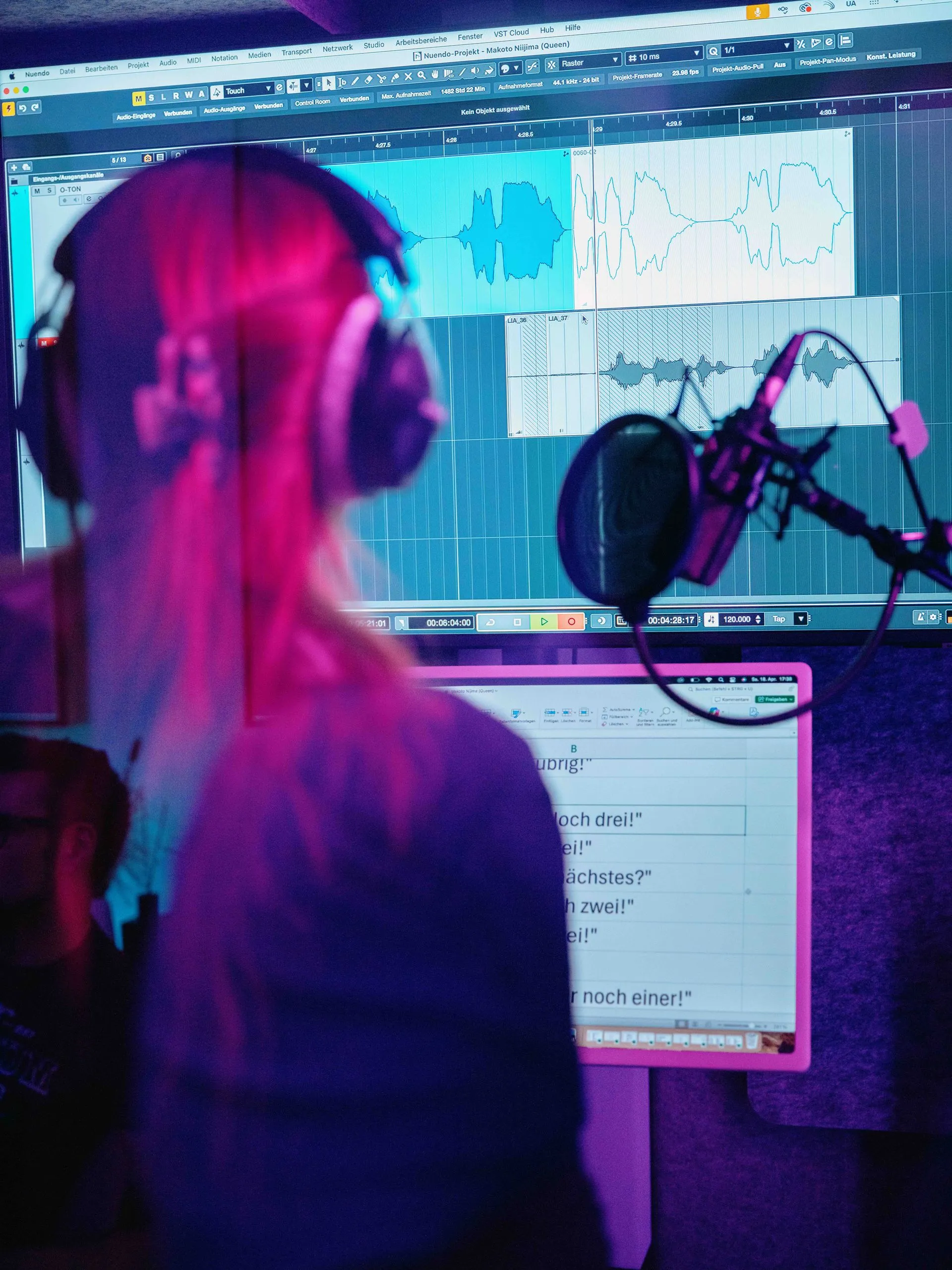 Ein Sprecher mit Kopfhörern sitzt vor einem Bildschirm, auf dem eine Audio-Wellenform und ein Textdokument zu sehen sind.